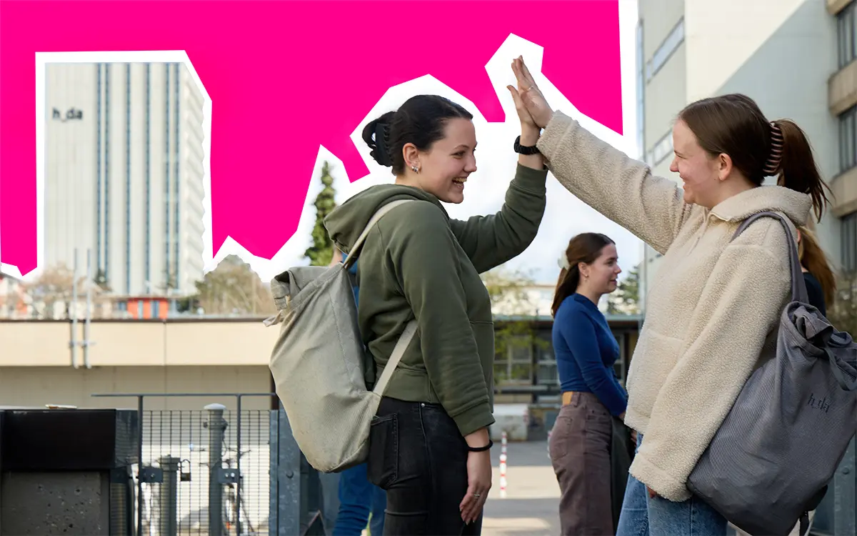 2 Studentinnen begrüßen sich, das Hochhaus der Hochschule Darmstadt ist im Hintergrund