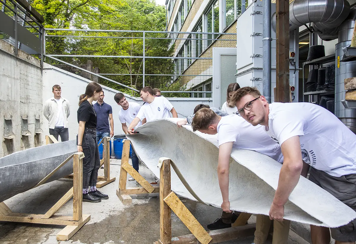 Studierende am selbst gebauten Betonkanu im Studiengang Bauingenieurwesen der h_da, Hochschule Darmstadt.