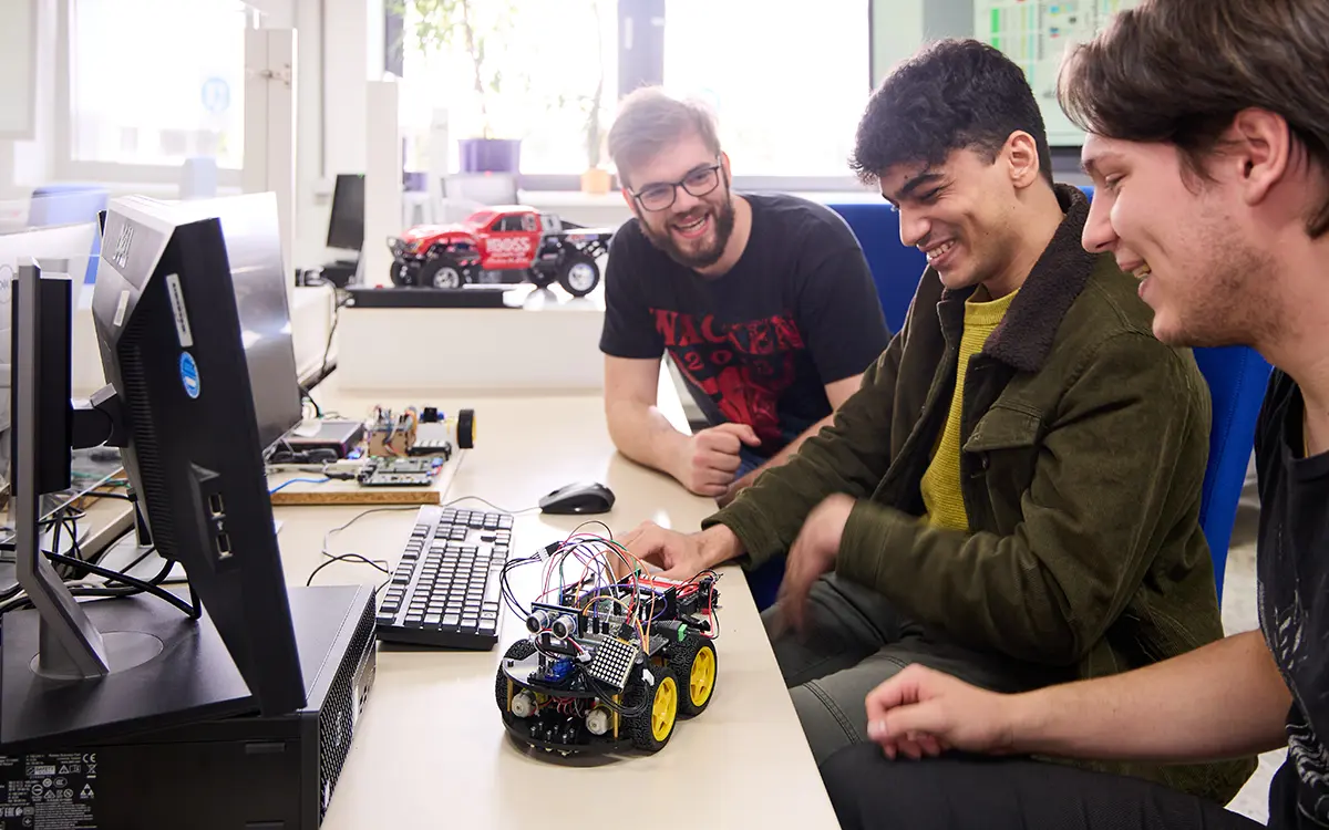 Studierende experimentieren im Labor mit einem mit Sensoren ausgestatteten Modellauto. Situation am Fachbereich Informatik der h_da, Hochschule Darmstadt. 