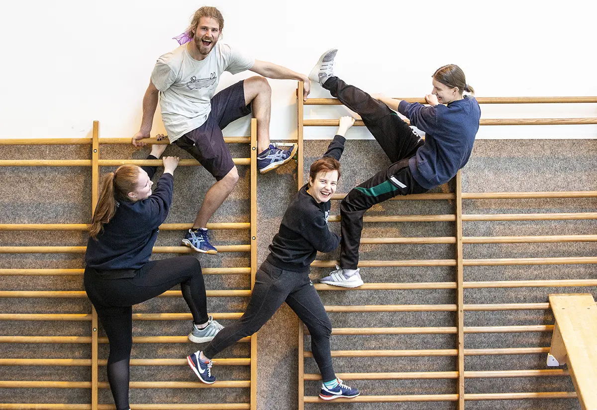 Studierende bilden Formation an einer Sprossenwand der Turnhalle. Studiengang Soziale Arbeit PLUS Psychomotorik der h_da, Hochschule Darmstadt.